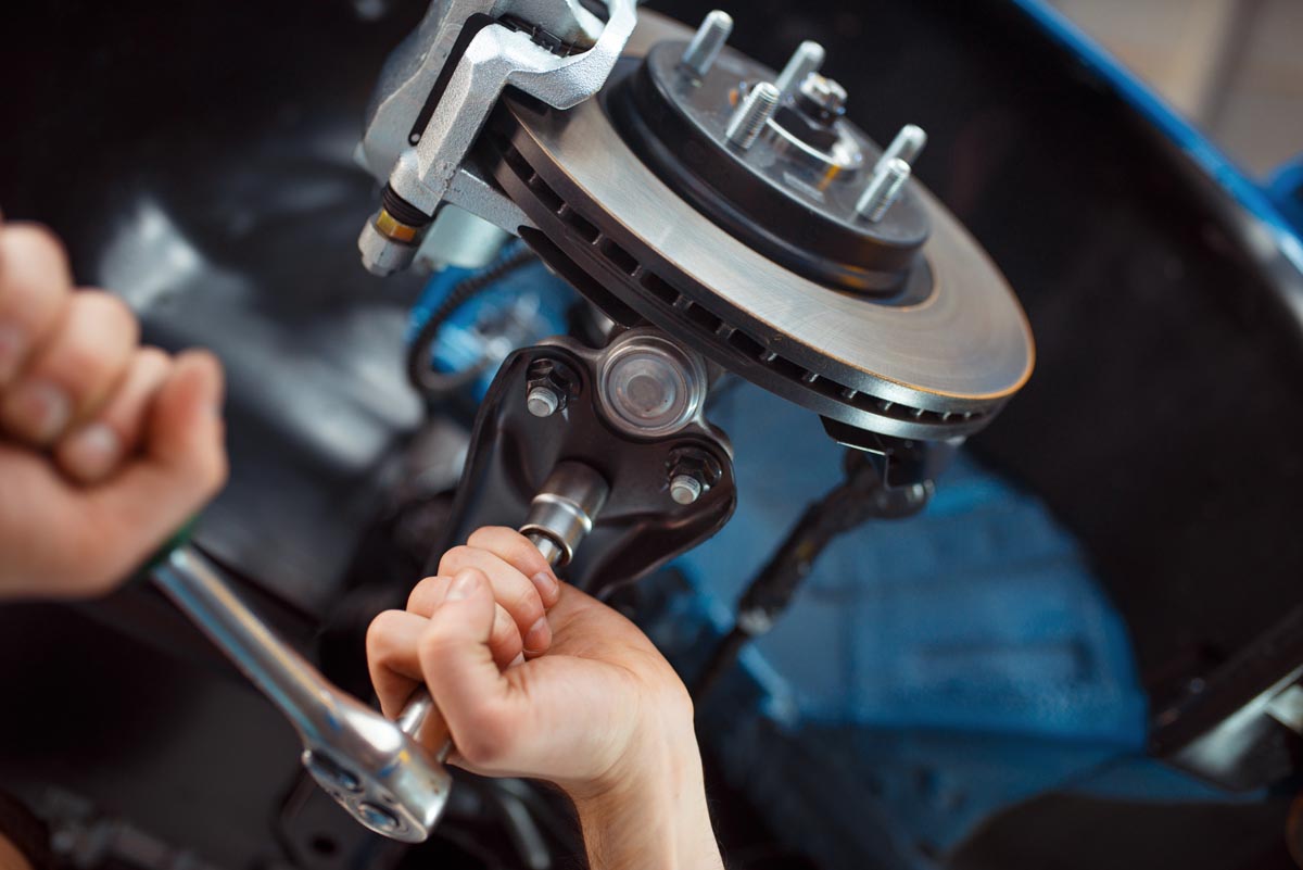 Worker repairing vehicle on lift, car service